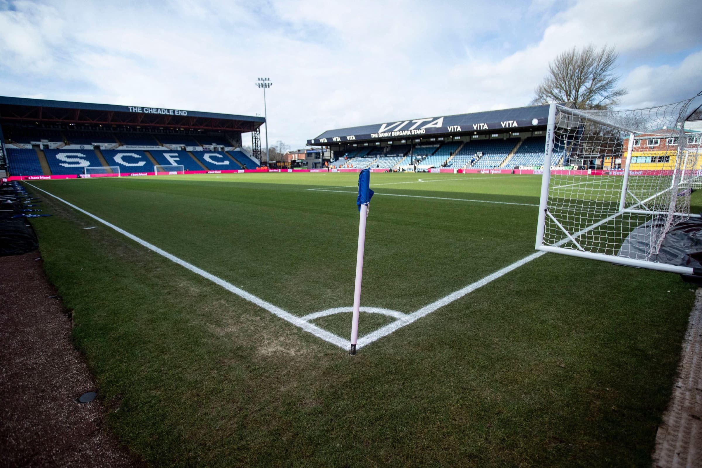 A quiet football ground, the corner flag in front of an empty stand